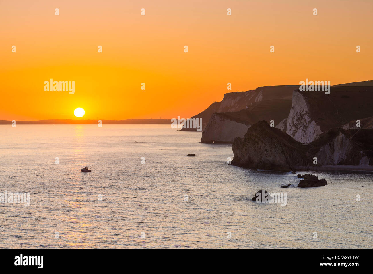 Dungy Head, West Lulworth, Dorset, UK.  18th September 2019.  UK Weather. Clear skies at sunset as the sky turns bright orange at Dungy Head at West Lulworth on the Dorset Jurassic Coast with a view along the cliffs towards Durdle Door (Near), Bats Head (Middle) and White Nothe (Far).  Picture Credit: Graham Hunt/Alamy Live News Stock Photo