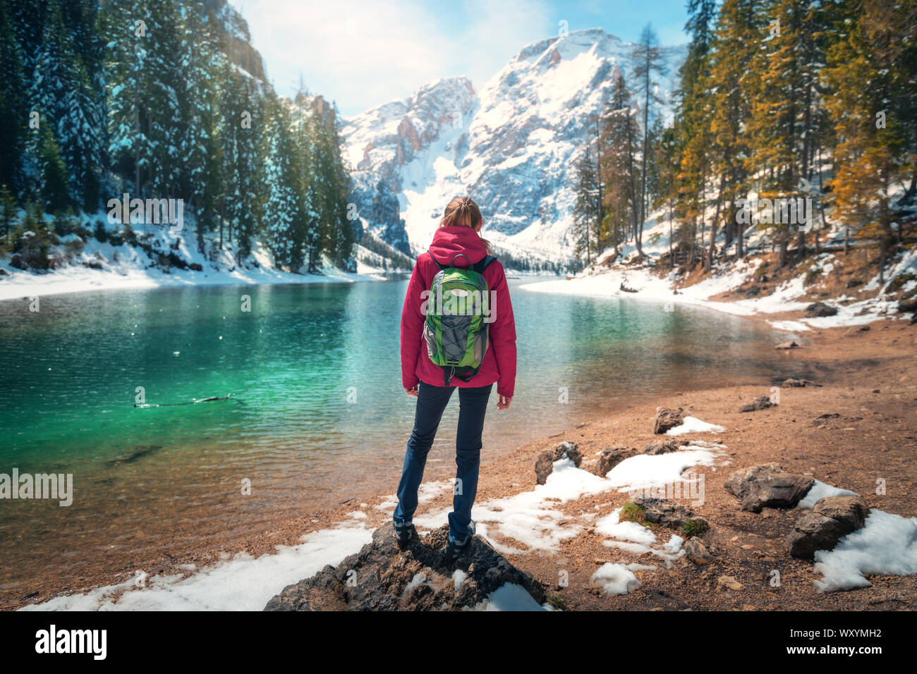 Woman with backpack on the stone near lake with azure water Stock Photo