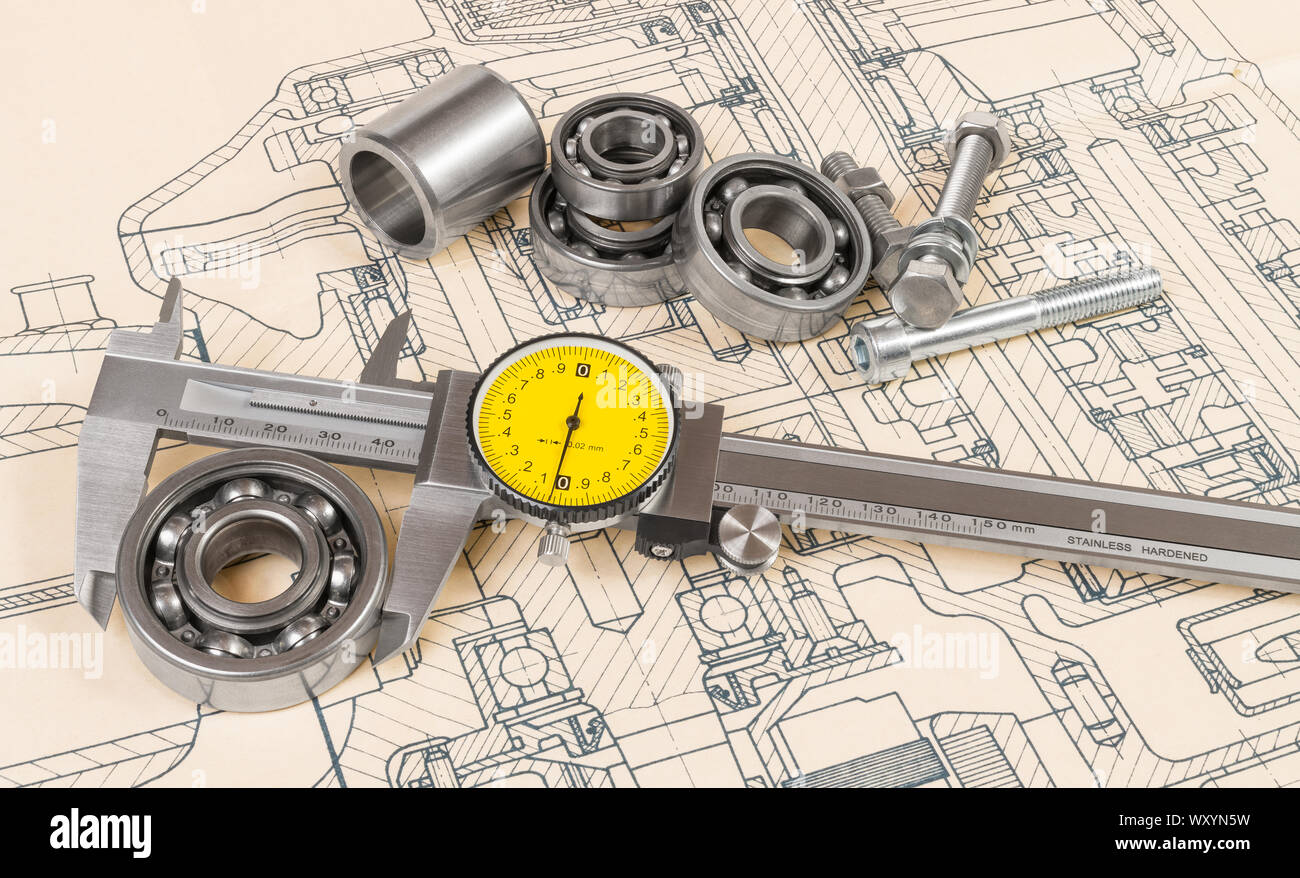 Analog caliper detail. Accurate measuring of a ball bearing diameter on technical drawing background. Vernier gauge with round yellow dial. Metal tool. Stock Photo