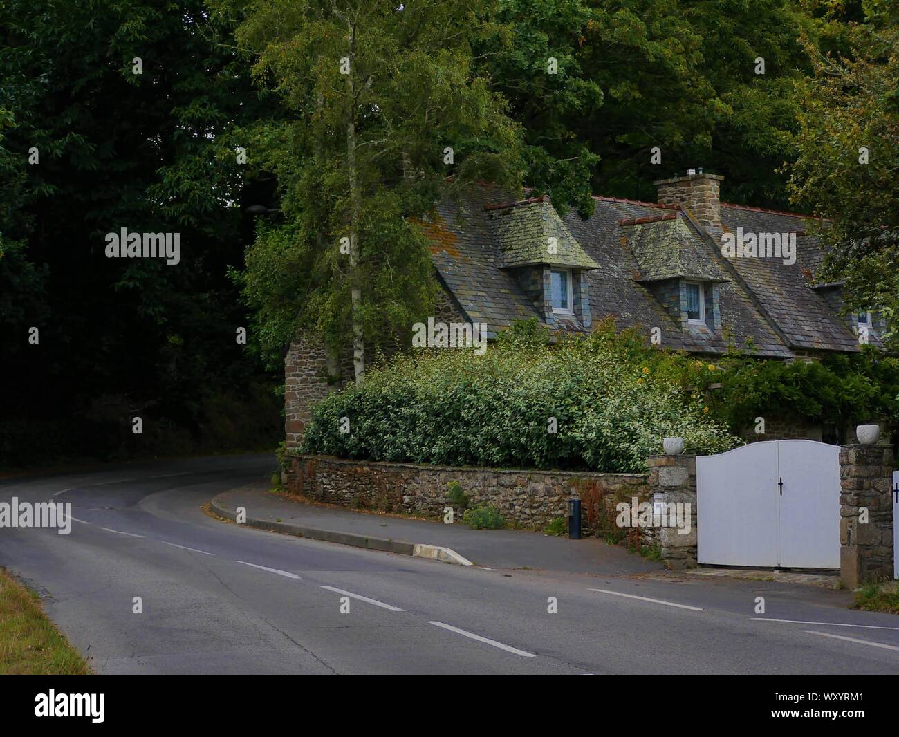 Belle maison bretonne au bord d'une route en pleine foret , ancienne maison traditionnelle au toit en ardoise , le conquet , bretagne , france Stock Photo