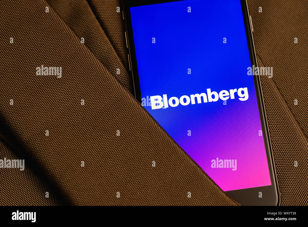 Black phone with logo of News media Bloomberg on the screen. News media icon. Canvas texture background. Illustration editorial Stock Photo