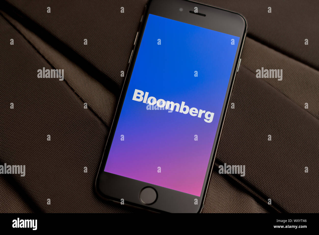 Black phone with logo of News media Bloomberg on the screen. News media icon. Canvas texture background. Illustration editorial Stock Photo