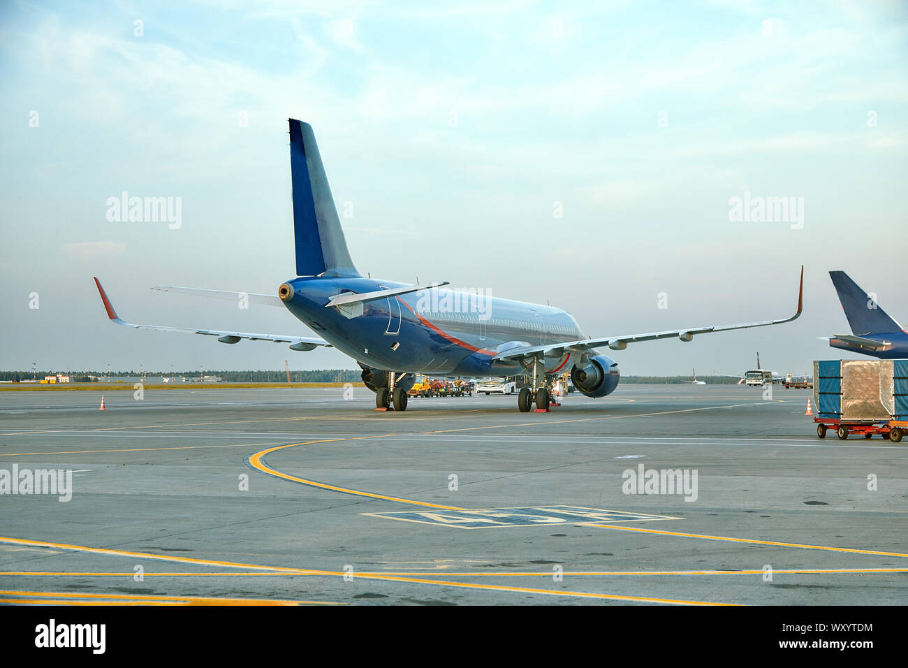 Modern passenger airplane parked to terminal building gate at airside apron of airport with close up airplane parts jet engine wing windows gear tow t Stock Photo