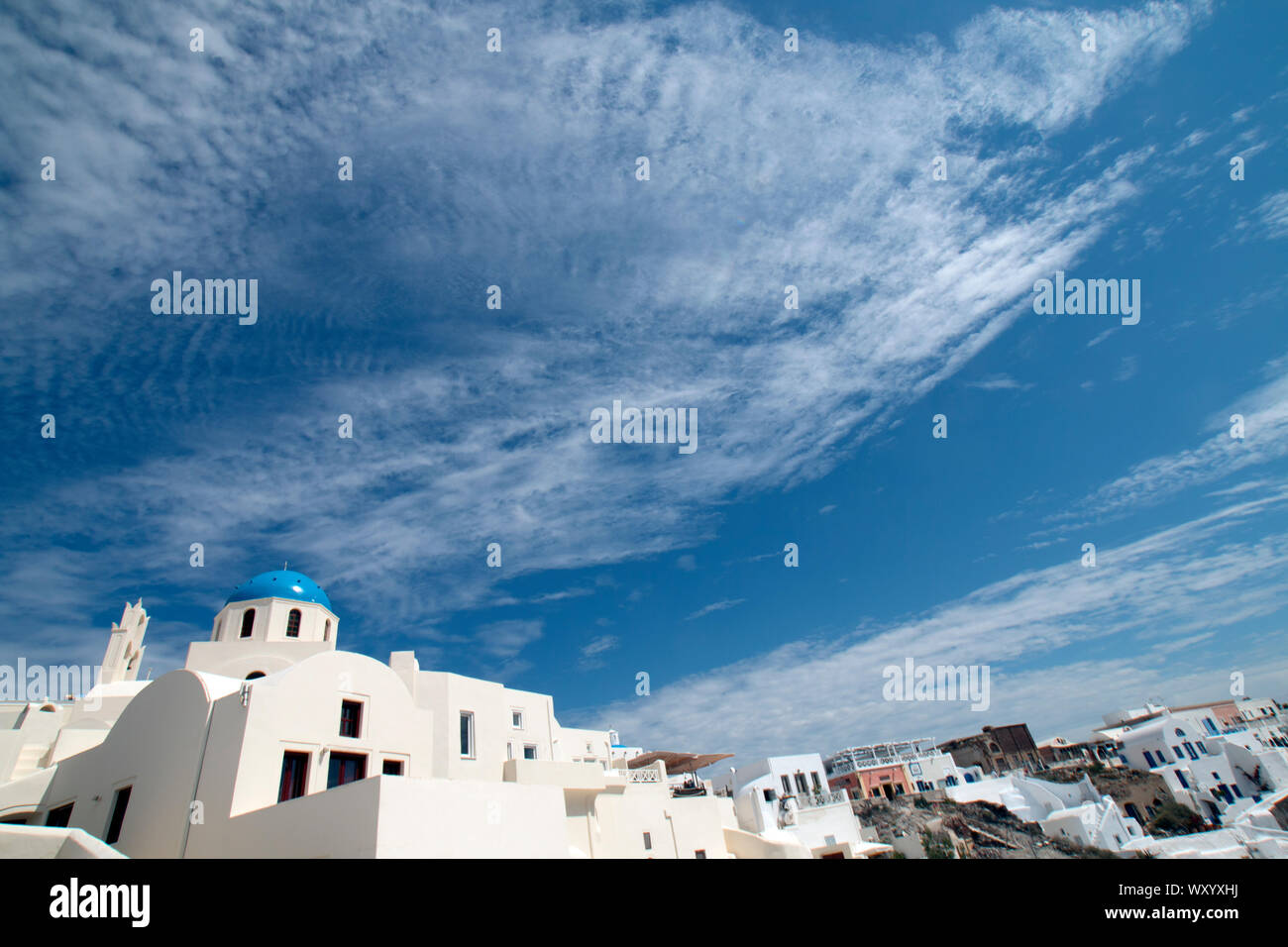 Looking to the sky over the whitewashed buildings with blue roofs on the Greek Island of Santorini Stock Photo
