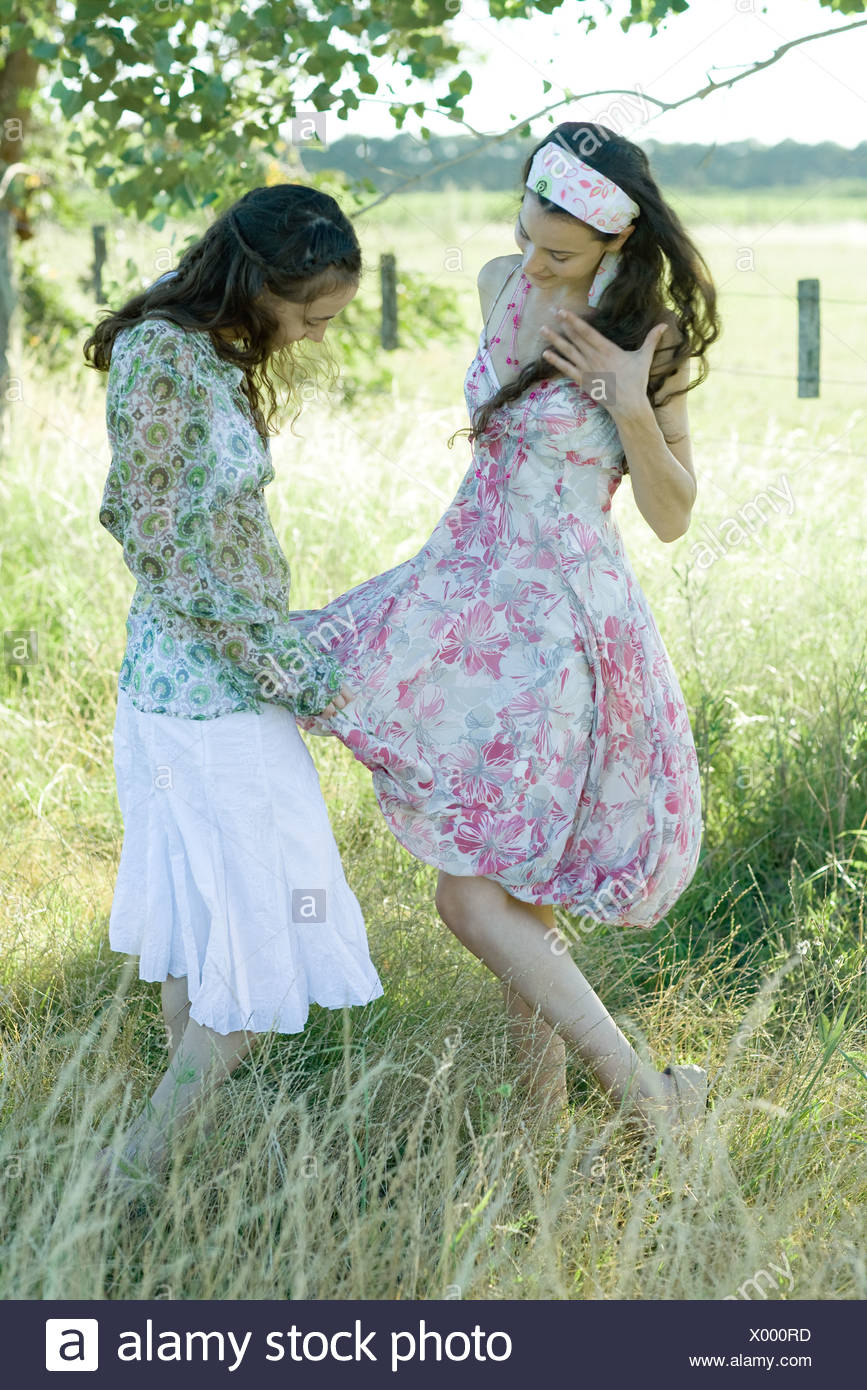 Two Young Women Standing In Field One Looking At The Other S Dress Stock Photo Alamy