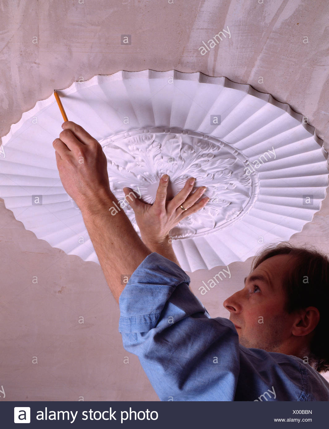 Close Up Of Man Replacing Plaster Ceiling Rose Stock Photo