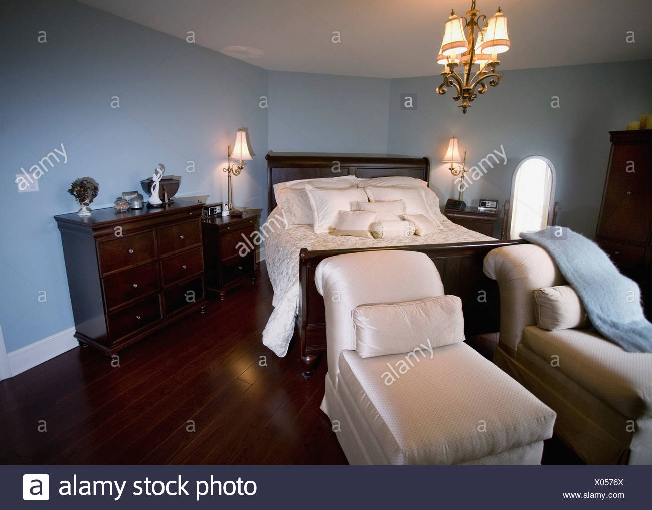 A Bedroom With Chaise Lounge Chairs At The Foot Of The Bed Stock