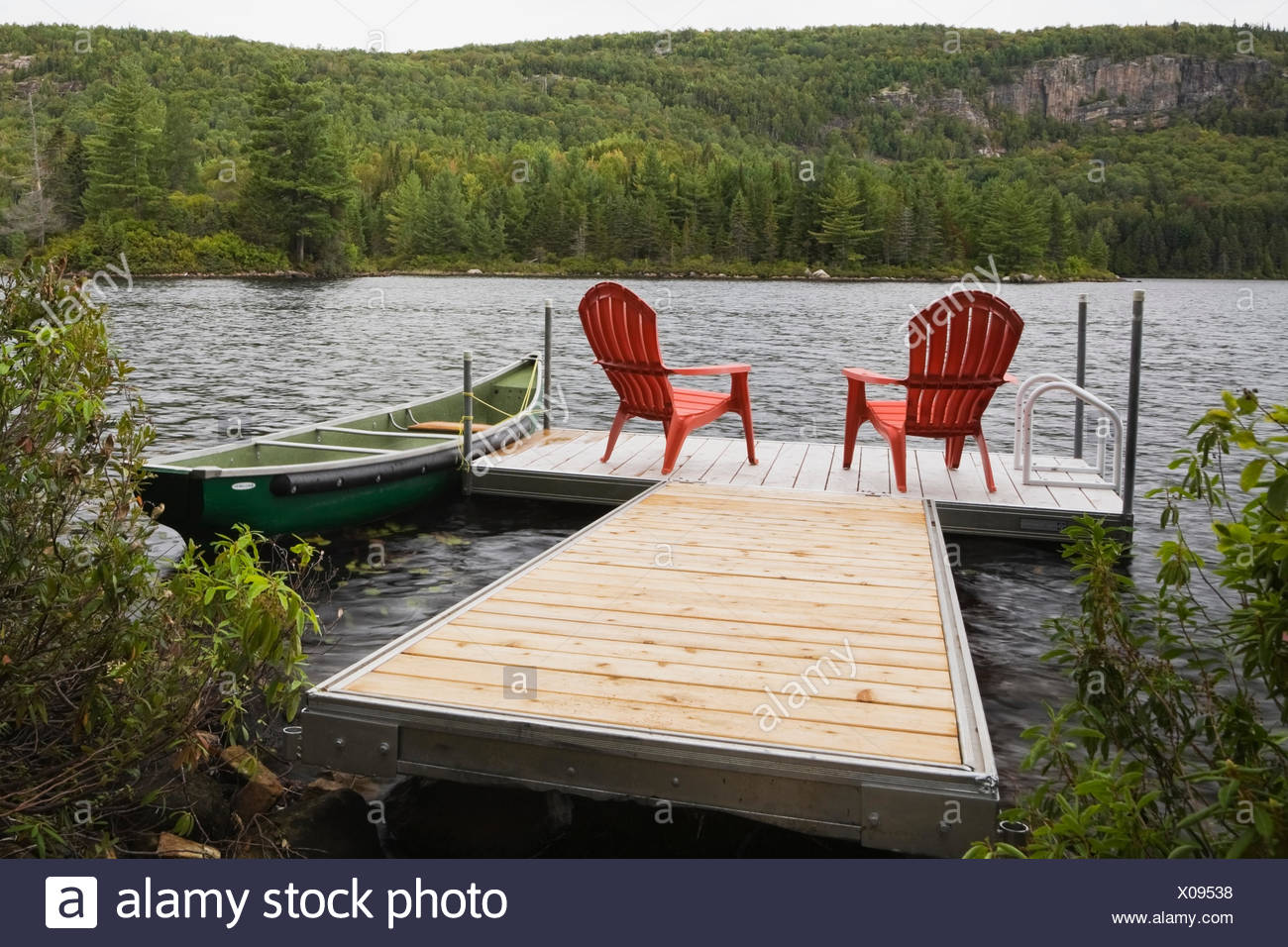 Two red adirondack chairs on floating dock on river Stock ...