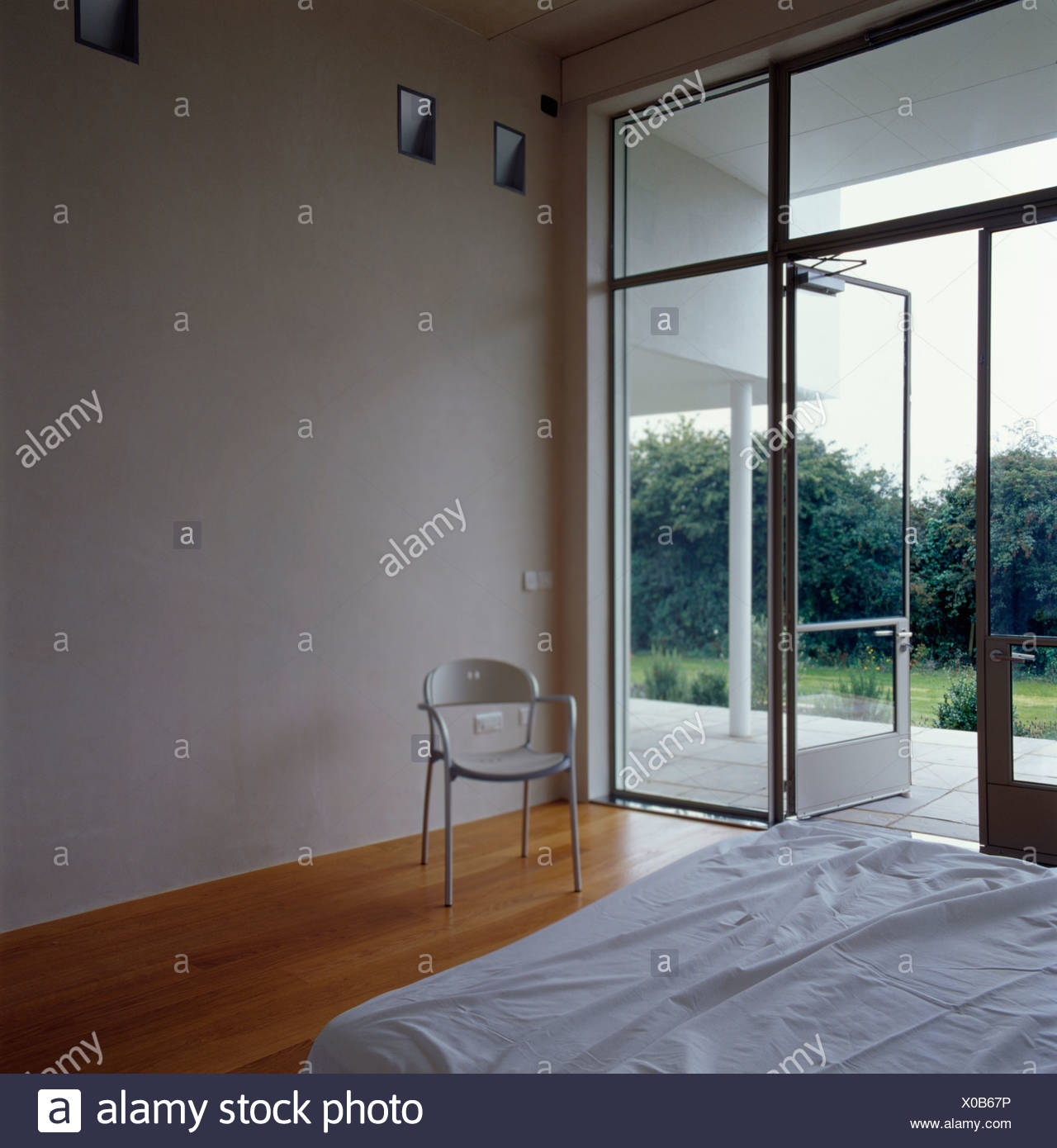 Small White Chair Beside Floor To Ceiling Window And Glass
