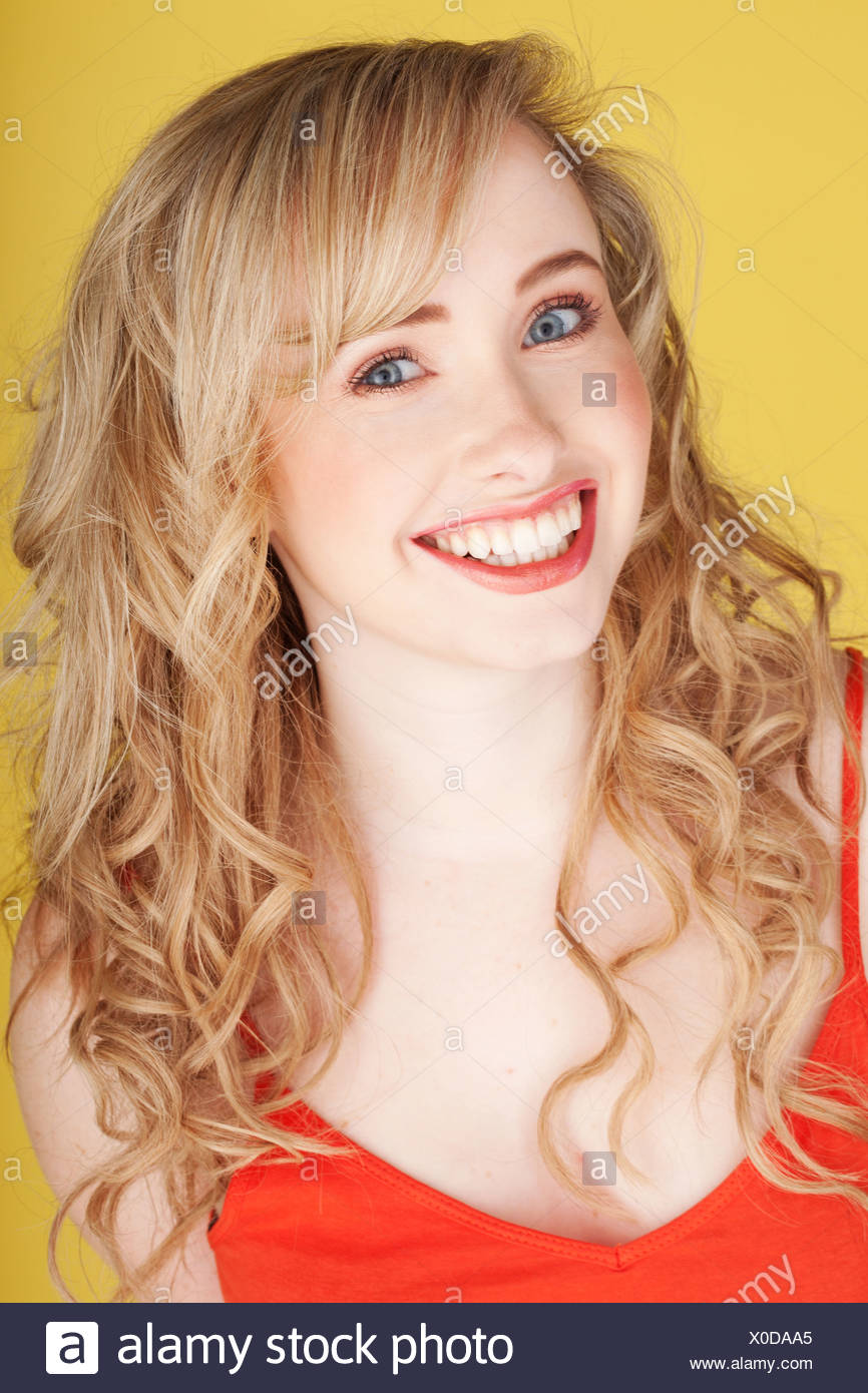 Happy Teenage Girl With Long Blonde Curly Hair Wearing A Red Tank