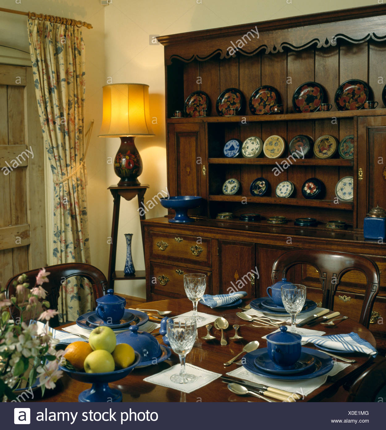 Blue Crockery On Table In Dining Room With Oak Dresser And Lighted