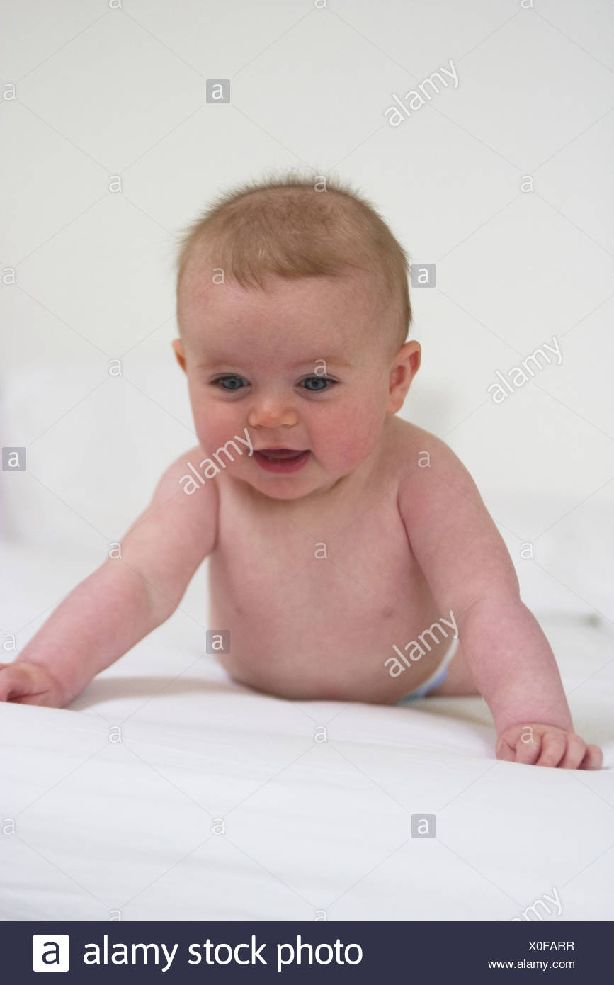 Female Baby With Spikey Hair Lying On Her Front On Bed Wearing
