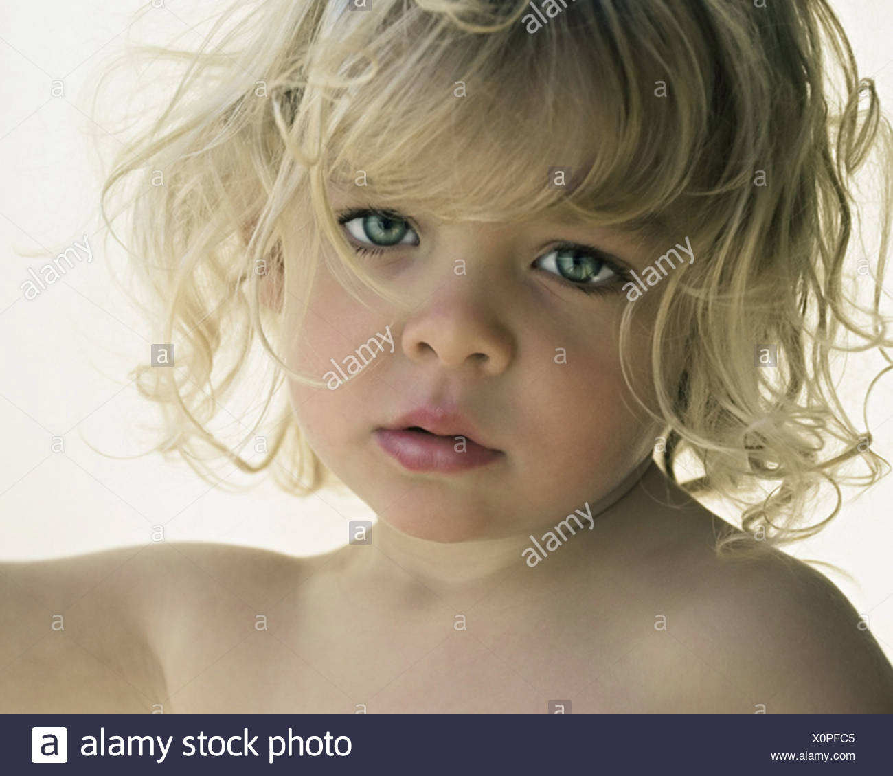 A Young Girl With Blonde Curly Hair And Blue Eyes Stock Photo