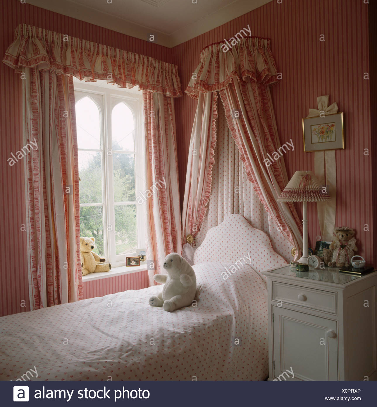 Bed With Coronet And Drapes Beside Window In Childs Bedroom