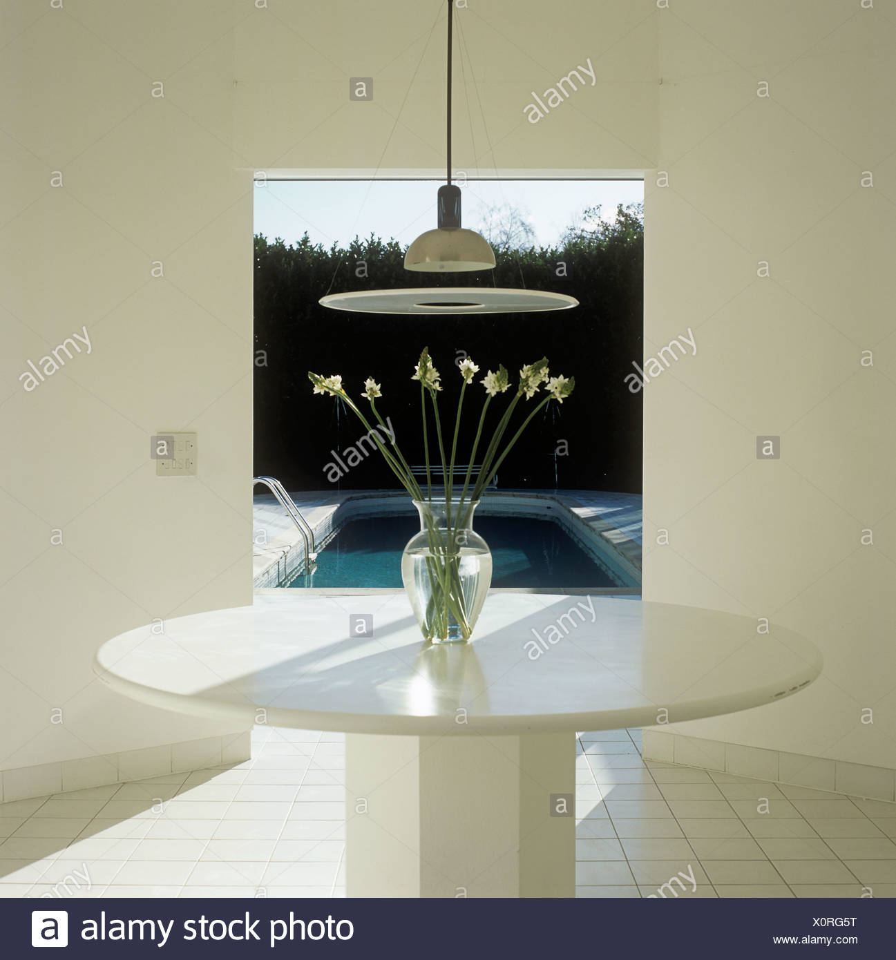 Light Suspended Over White Table In Minimalist Dining Room With White Tiled Floor And View Of Swimming Pool Through Doorway Stock Photo Alamy Light Suspended Over White Table In Minimalist Dining Room With White Tiled Floor And View Of Swimming Pool Through Doorway Stock Photo Alamy