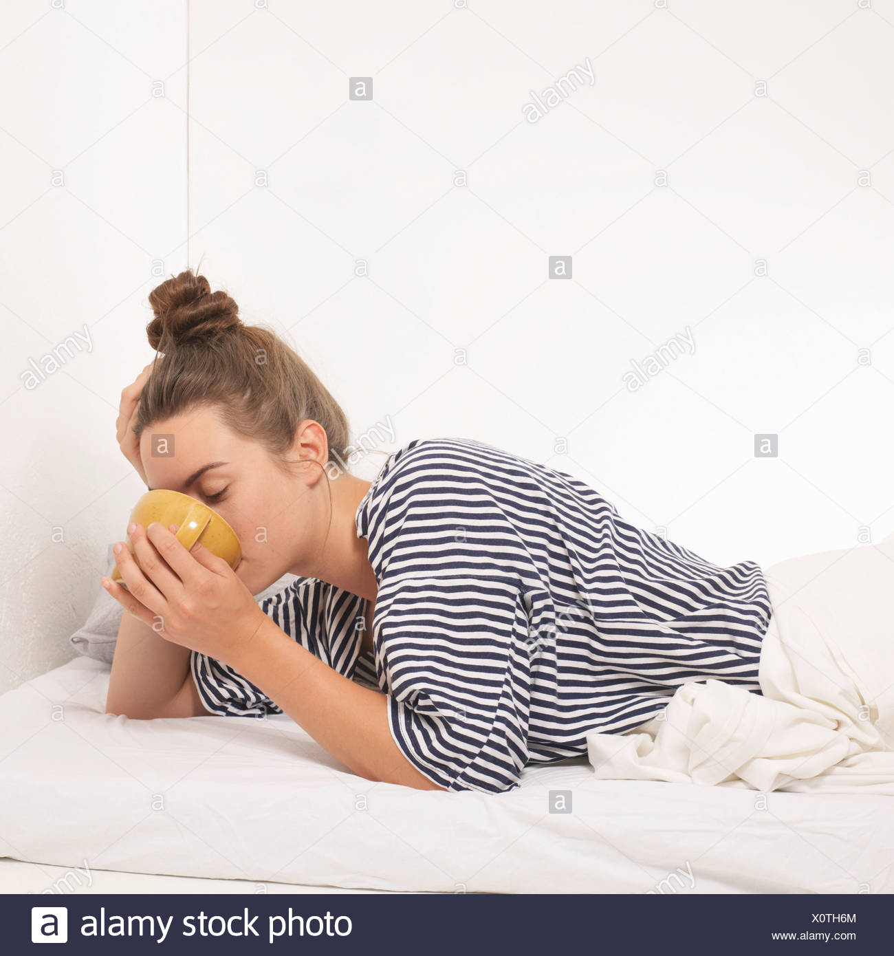 Woman in bed drinking from mug Stock Photo