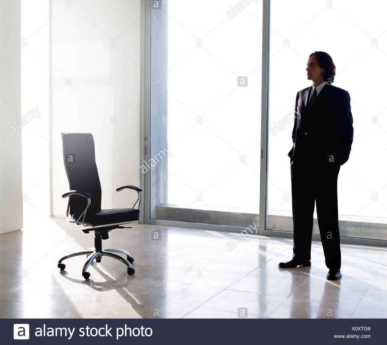 Businessman Wearing Dark Suit Standing Indoors Next To Office