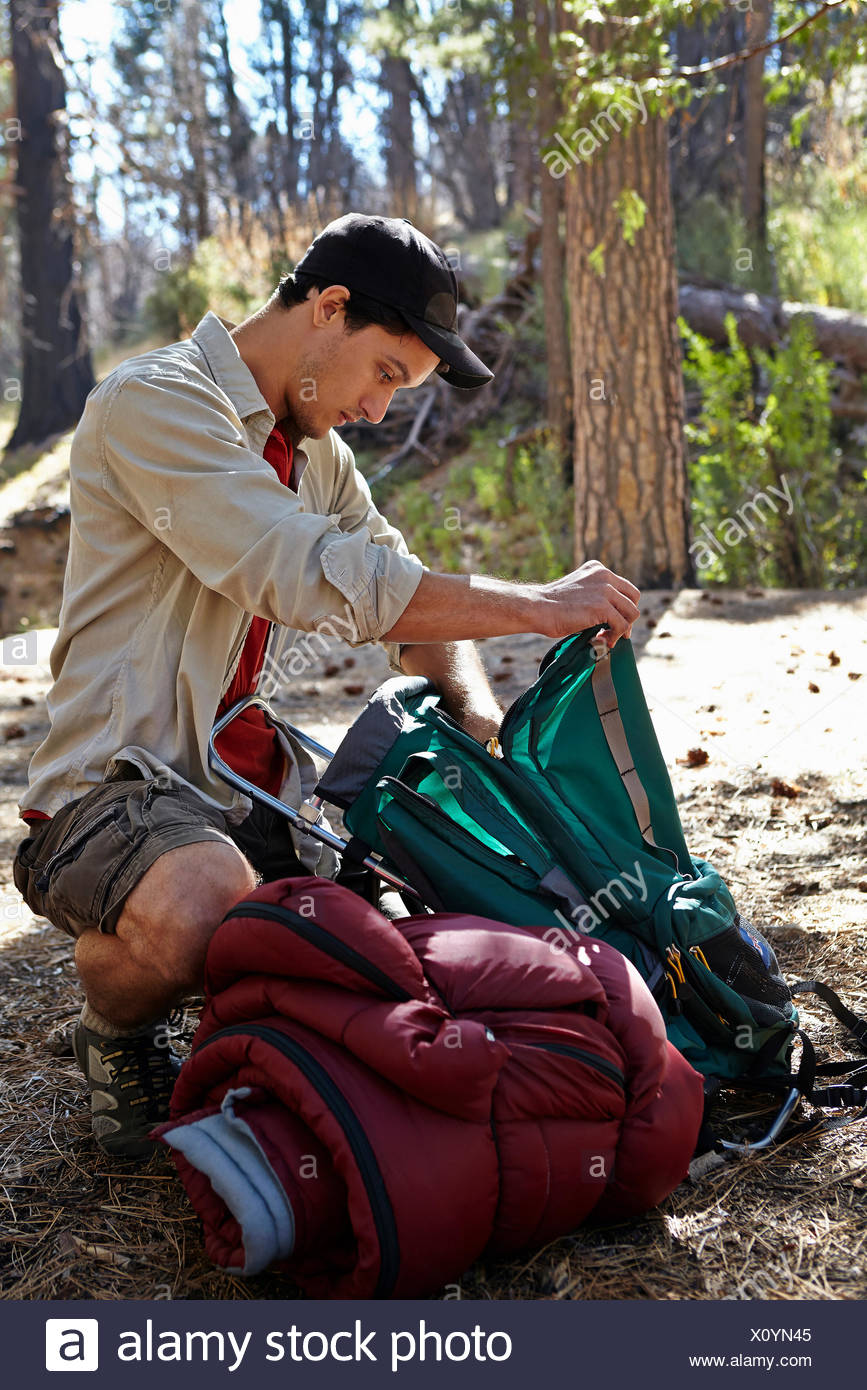 Young man in forest unpacking camping equipment, Los Angeles ...