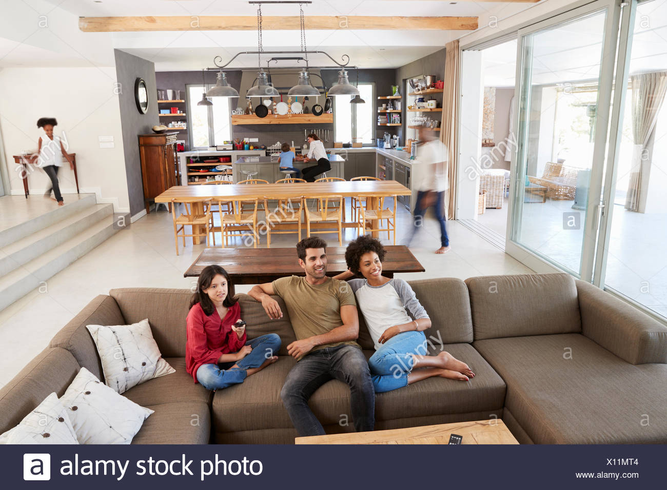 People Sitting On Sofa And Watching Tv In Busy Family Household