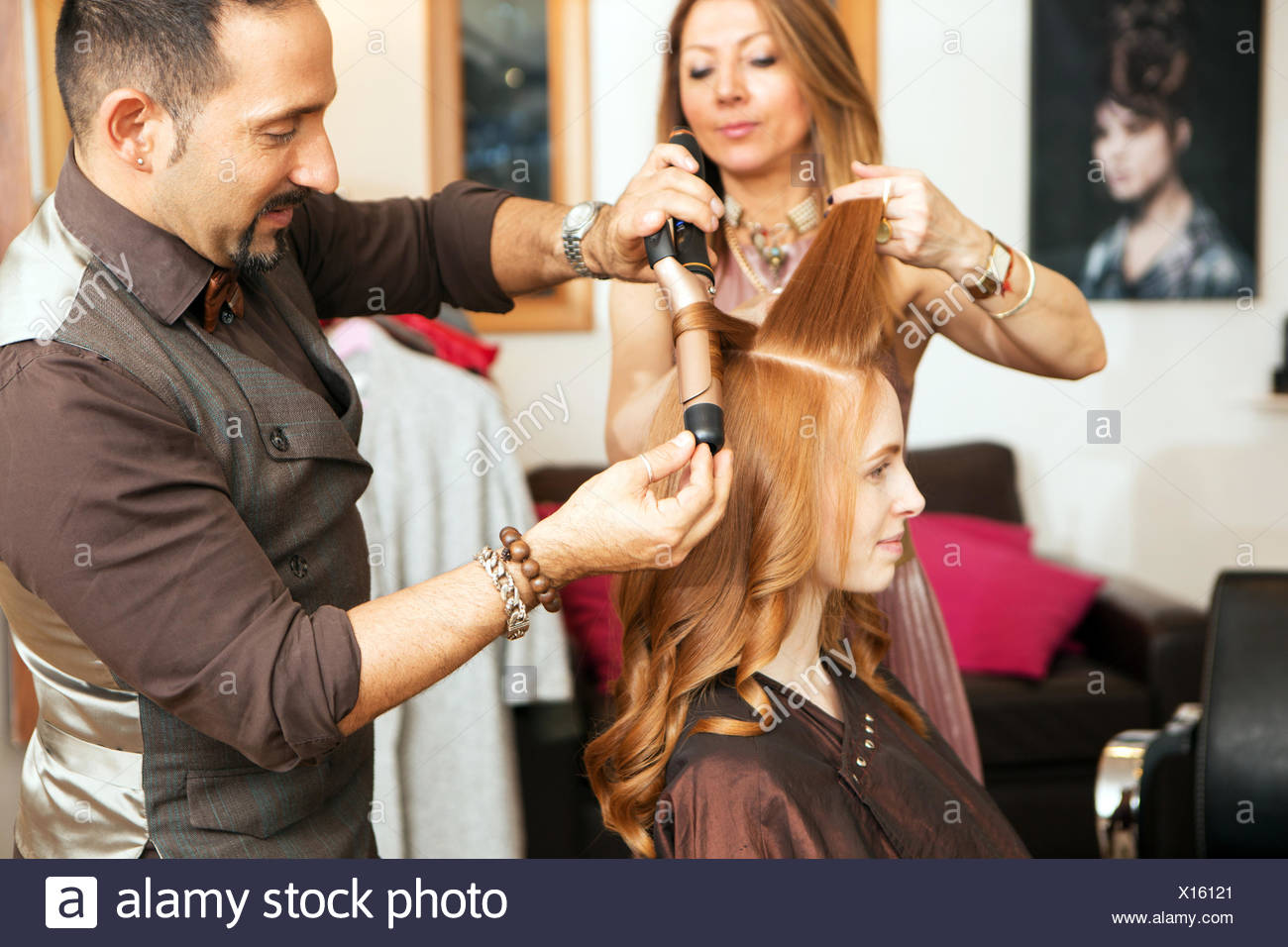 Hairdressers Using Curling Tongs On Customers Long Red Hair In