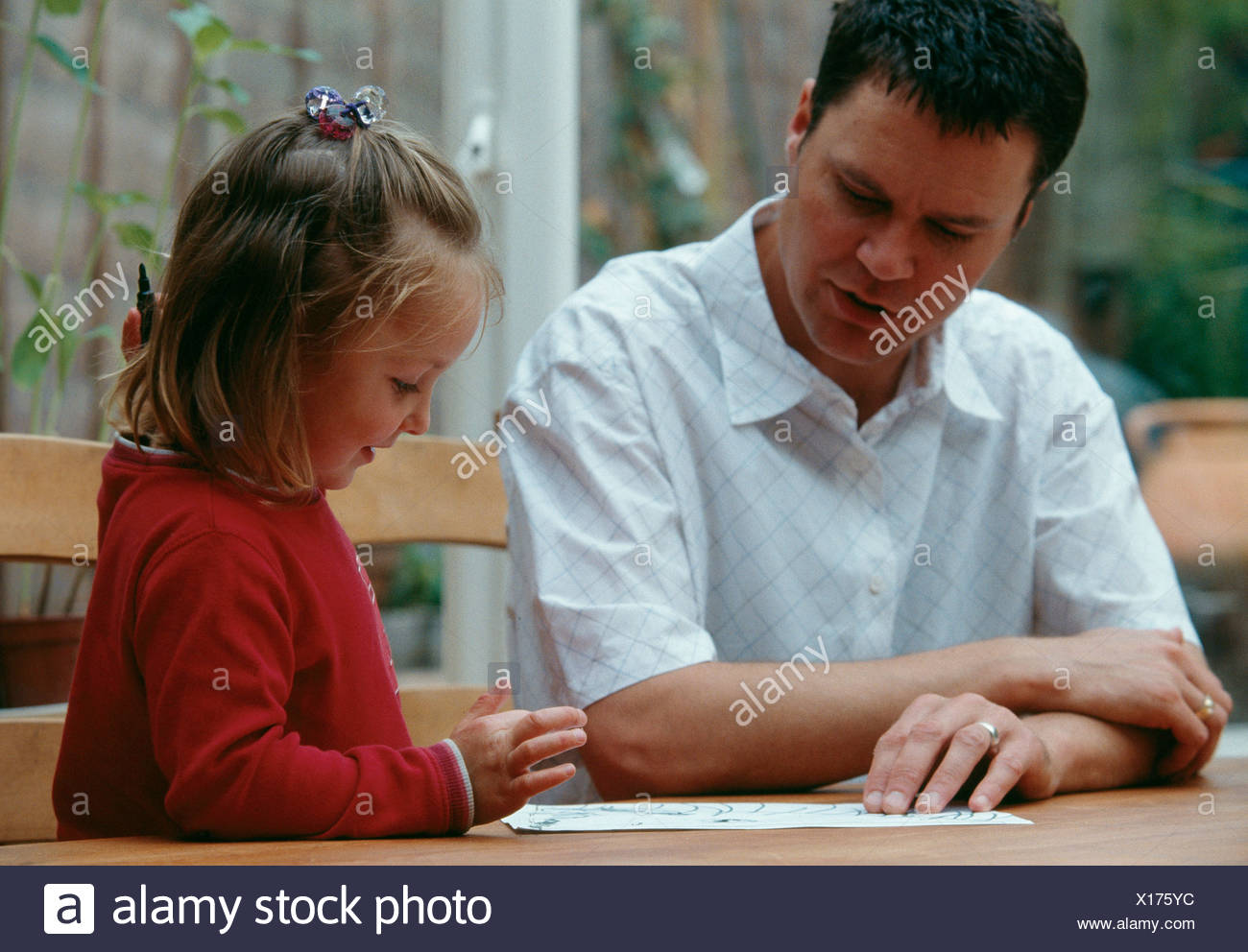 Father With Short Brown Hair Sitting At Table With Female Child