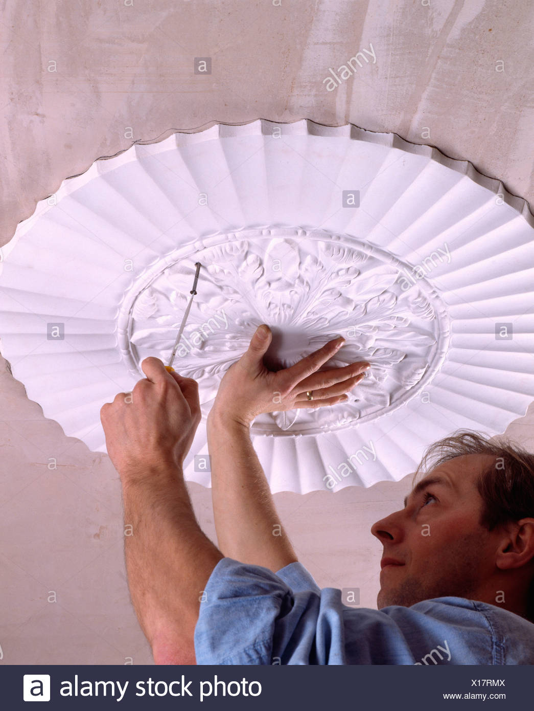Close Up Of Man Replacing Plaster Ceiling Rose Stock Photo