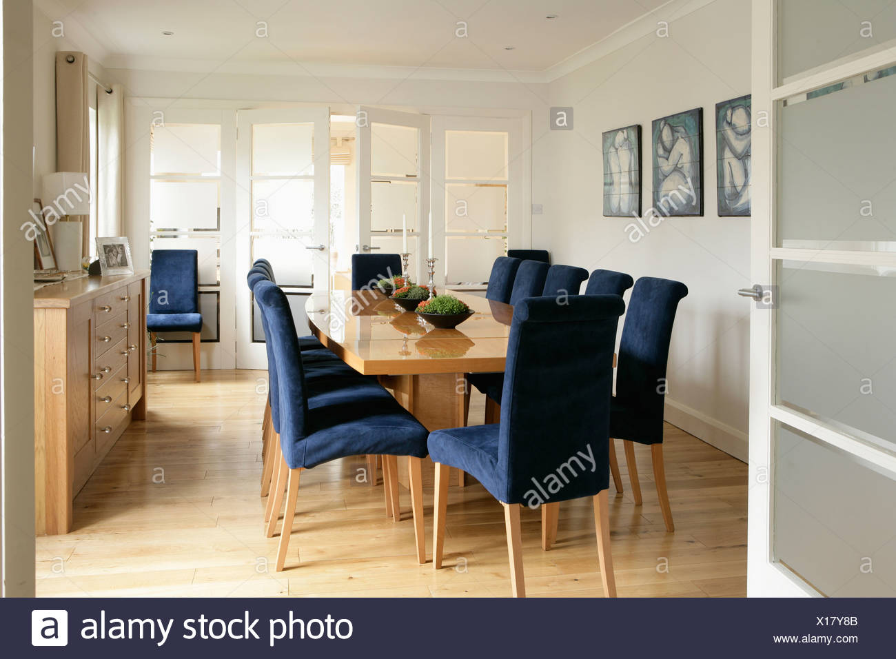 Glazed Door Open To Modern Dining Room With Blue Upholstered Chairs And Pale Wood Table And Wooden Flooring Stock Photo Alamy