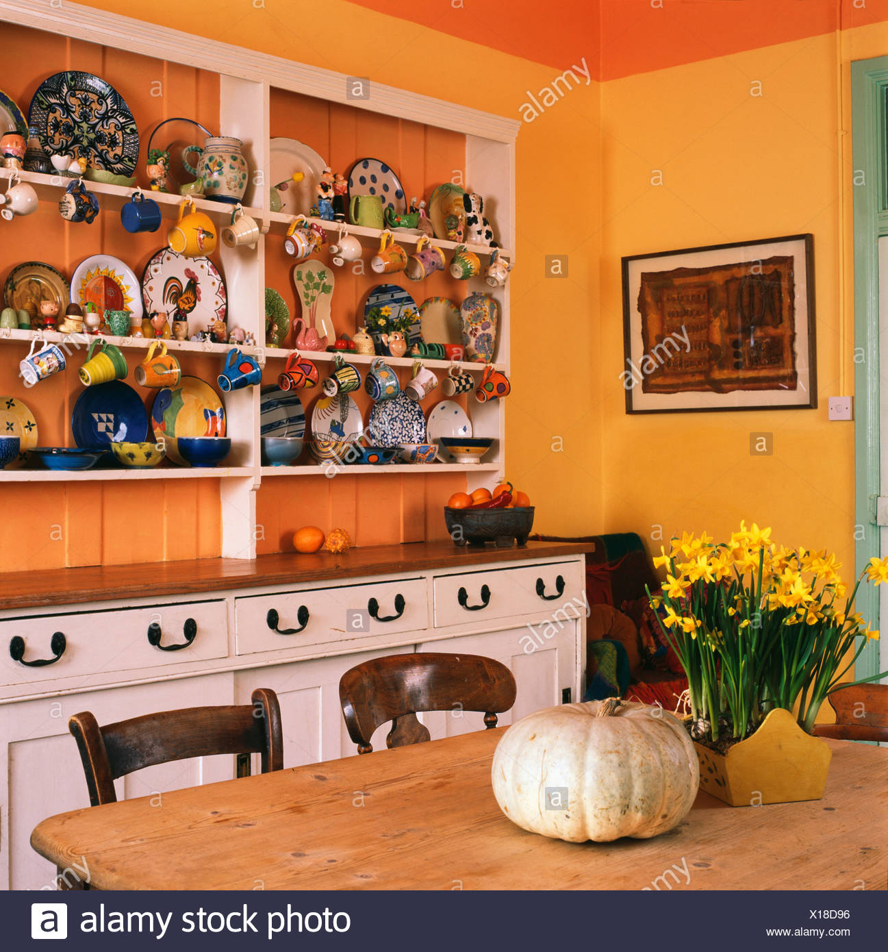Colourful Crockery On White Dresser In Orange Dining Room With