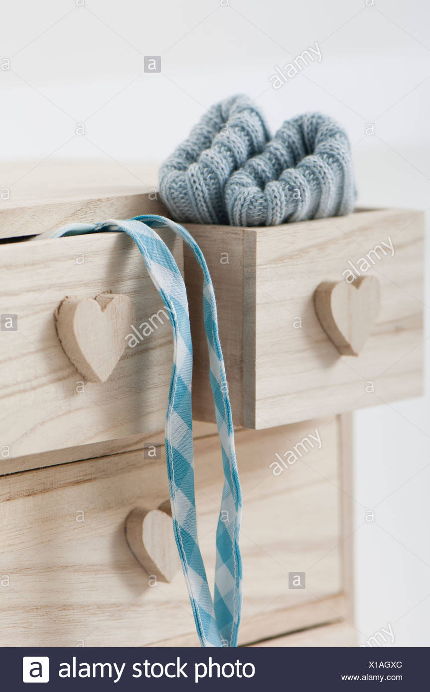Clothing Hanging Out Of Wooden Drawers With Heart Shaped Knobs