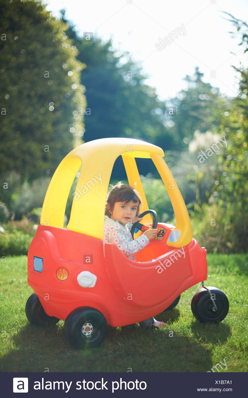 Female toddler playing in toy car in 