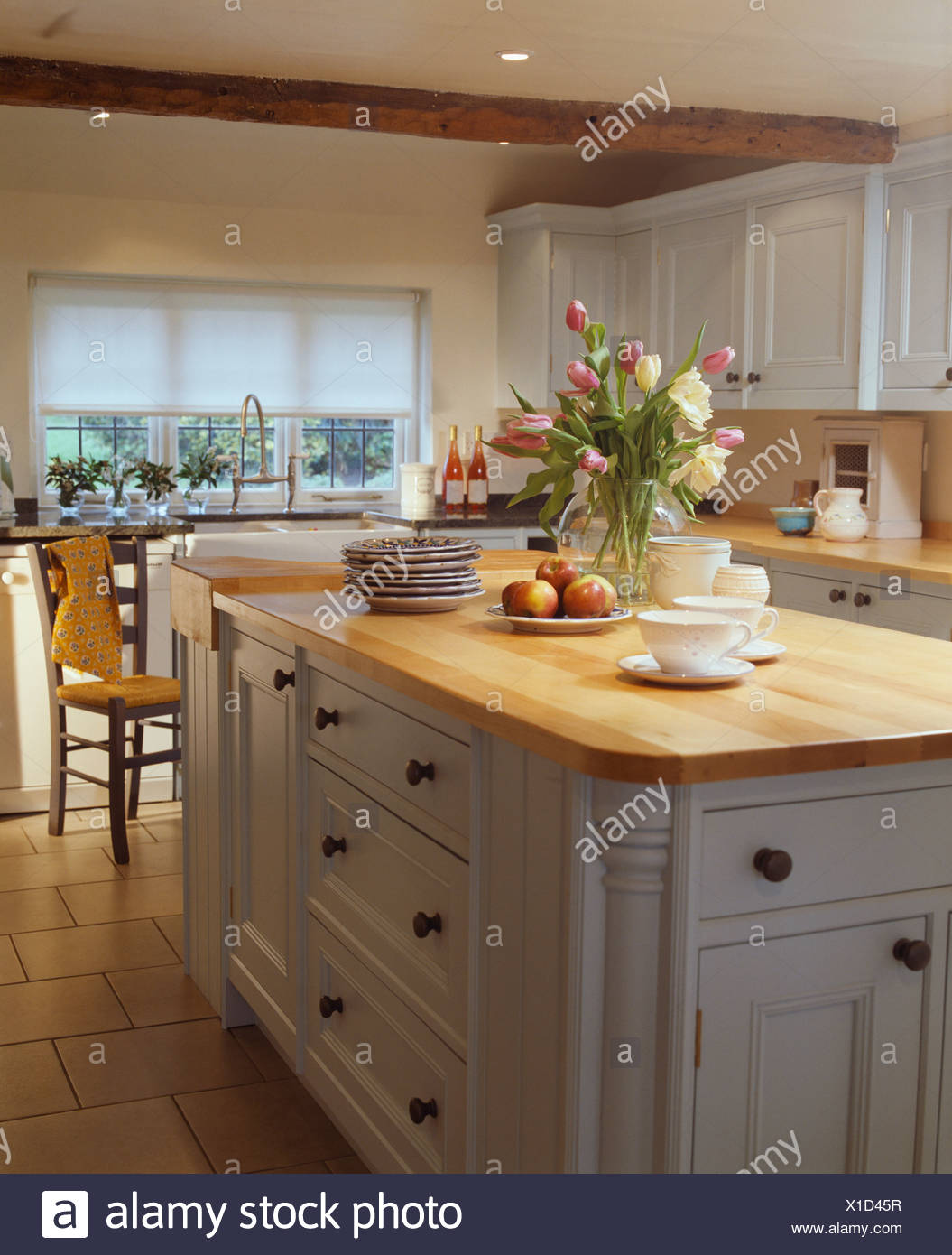 Vase Of Tulips On Island Unit With Wooden Worktop In White Country Kitchen With Pale Gray Fitted Units Stock Photo Alamy