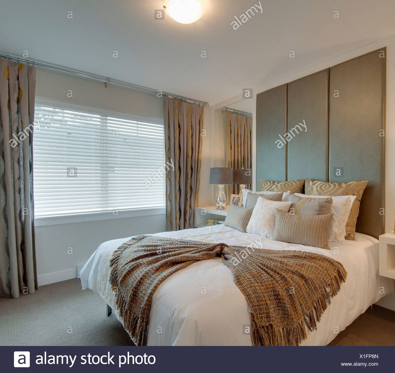 A Bed In A Bedroom Decorated With Cushions And A Blanket