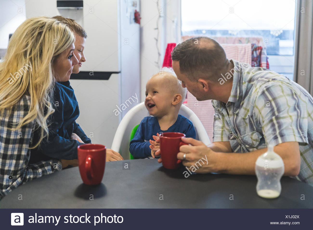Family Sitting Around Kitchen Table Young Toddler Sitting In