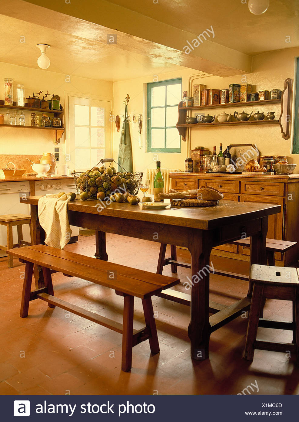Wooden Table And Benches In French Country Kitchen With Quarry