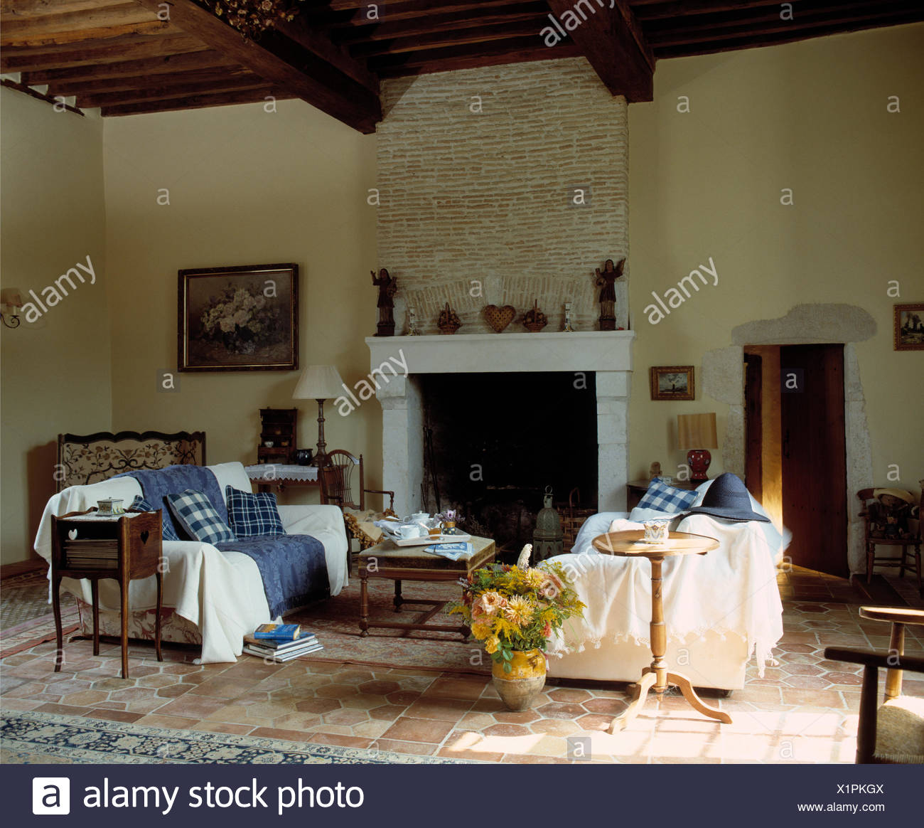 White Throws On Sofas On Either Side Of Stone Fireplace In French