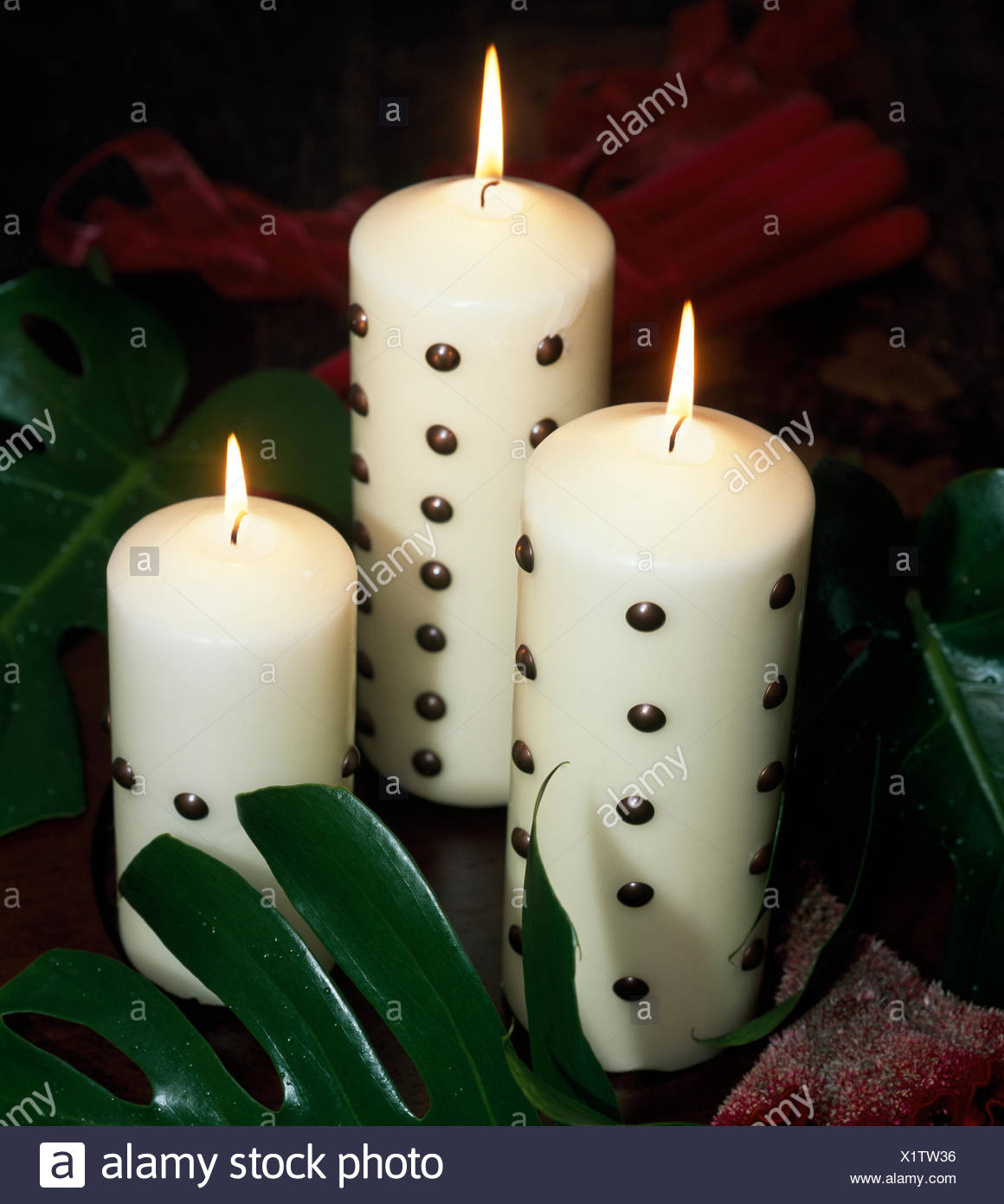 Close Up Of Three White Pillar Candles Decorated With Metal Studs