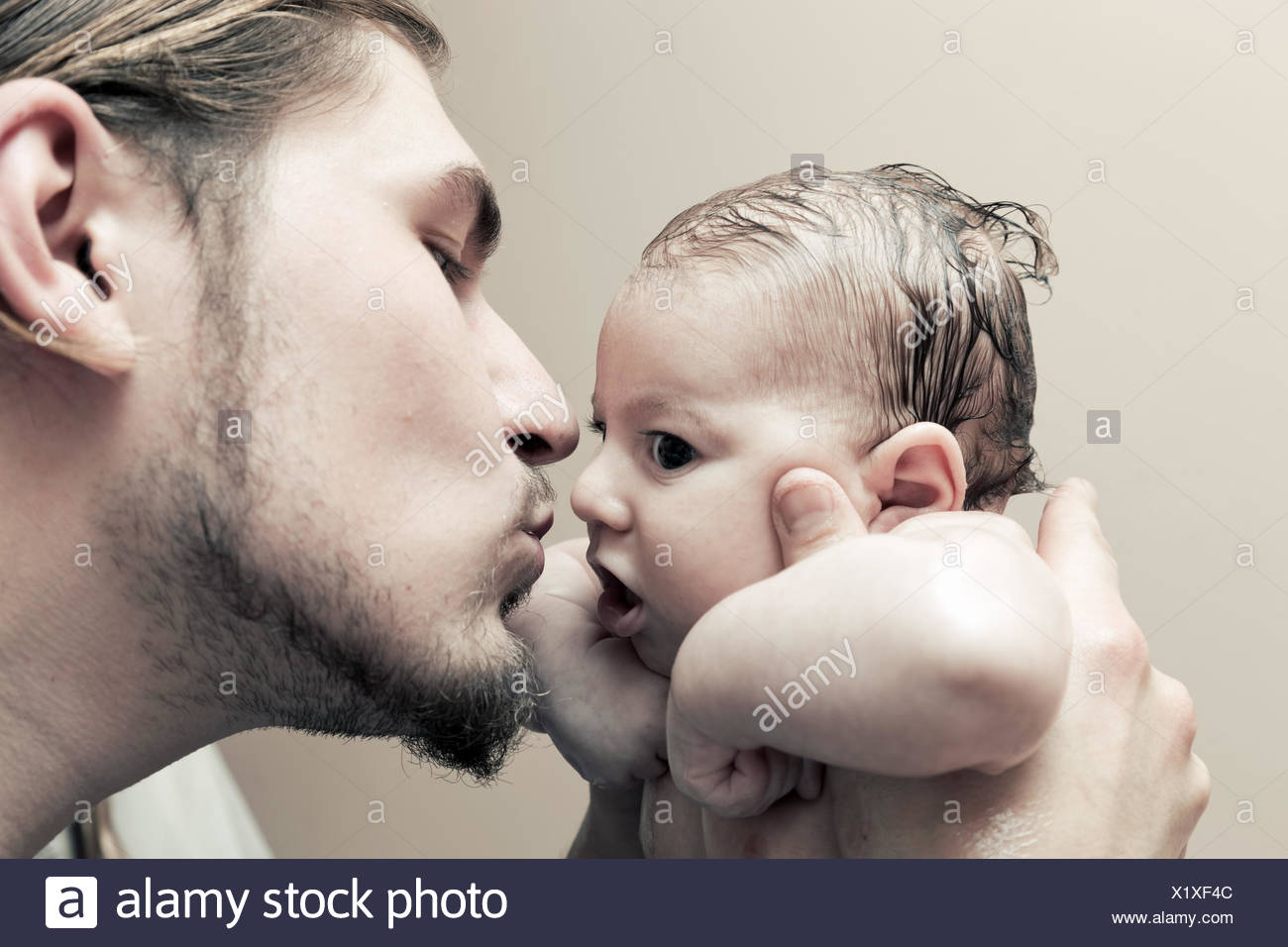 Father With His Young Baby Cuddling And Kissing Him On Cheek