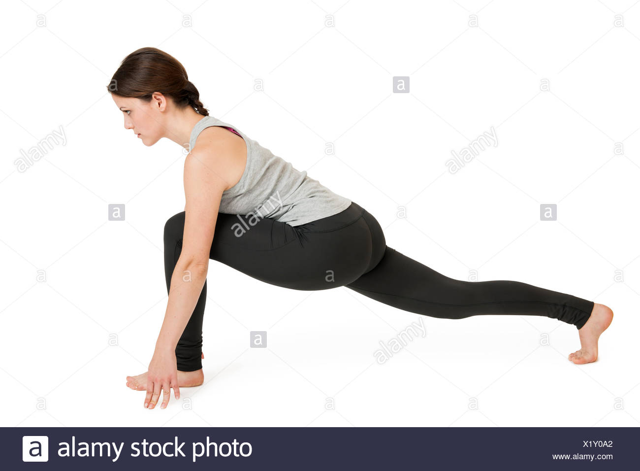 Seitliche Ganzkörper-Ansicht einer jungen Frau vor weißen Hintergrund die Yoga-Übung Ausfallschritt aus dem nach unten gerichteten Hund (adho mukha svanasana) zeigend. Stock Photo