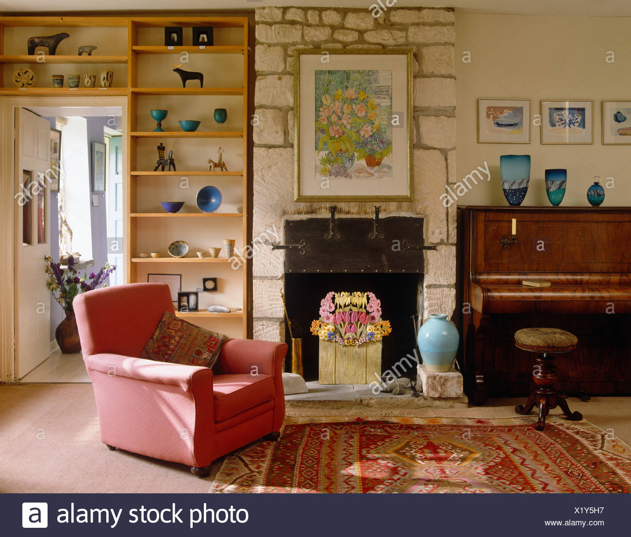 Pink Armchair And Open Wall Shelves In Country Living Room With
