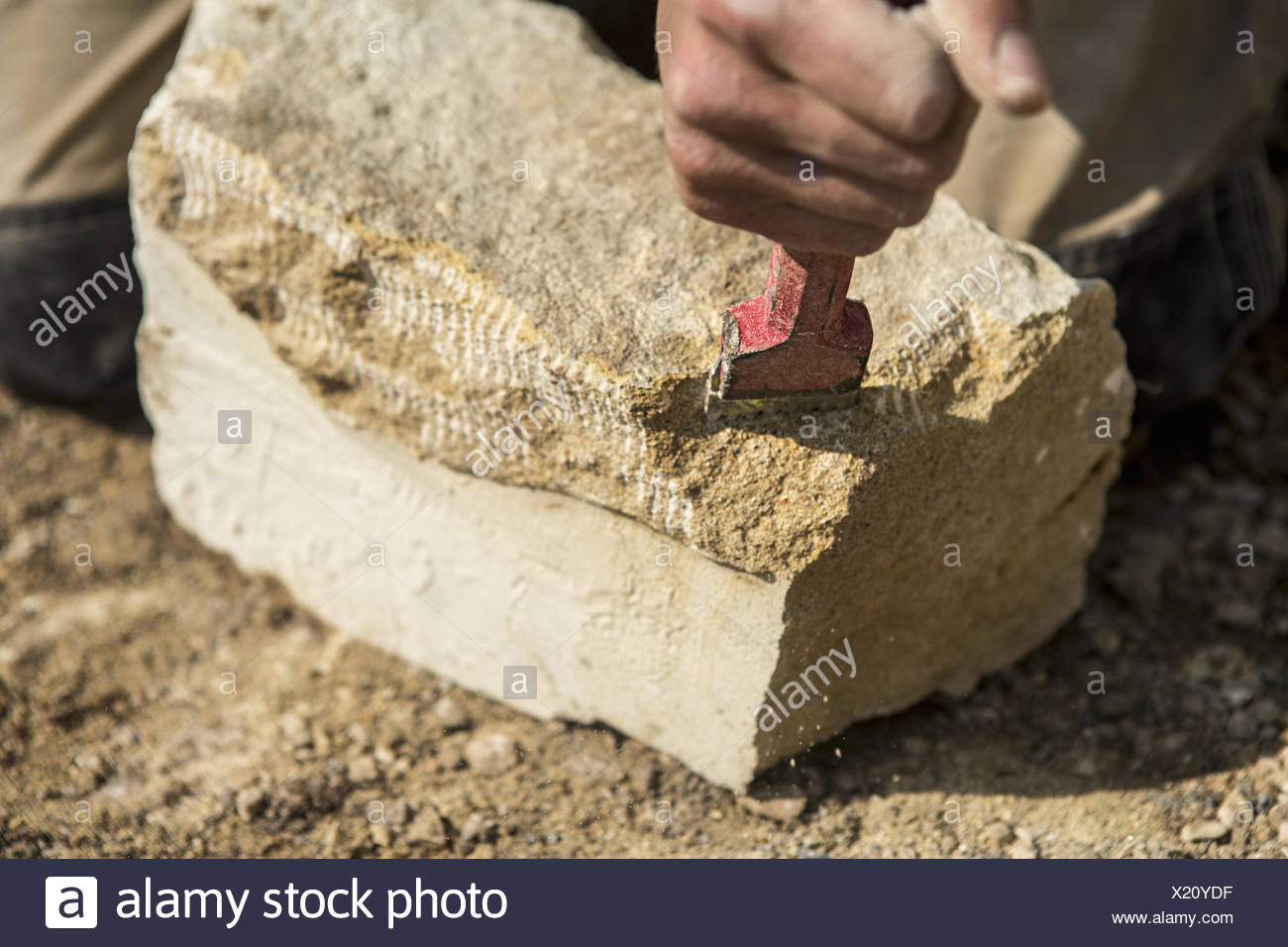 Construction worker holding a chisel, working on a stone Stock Photo