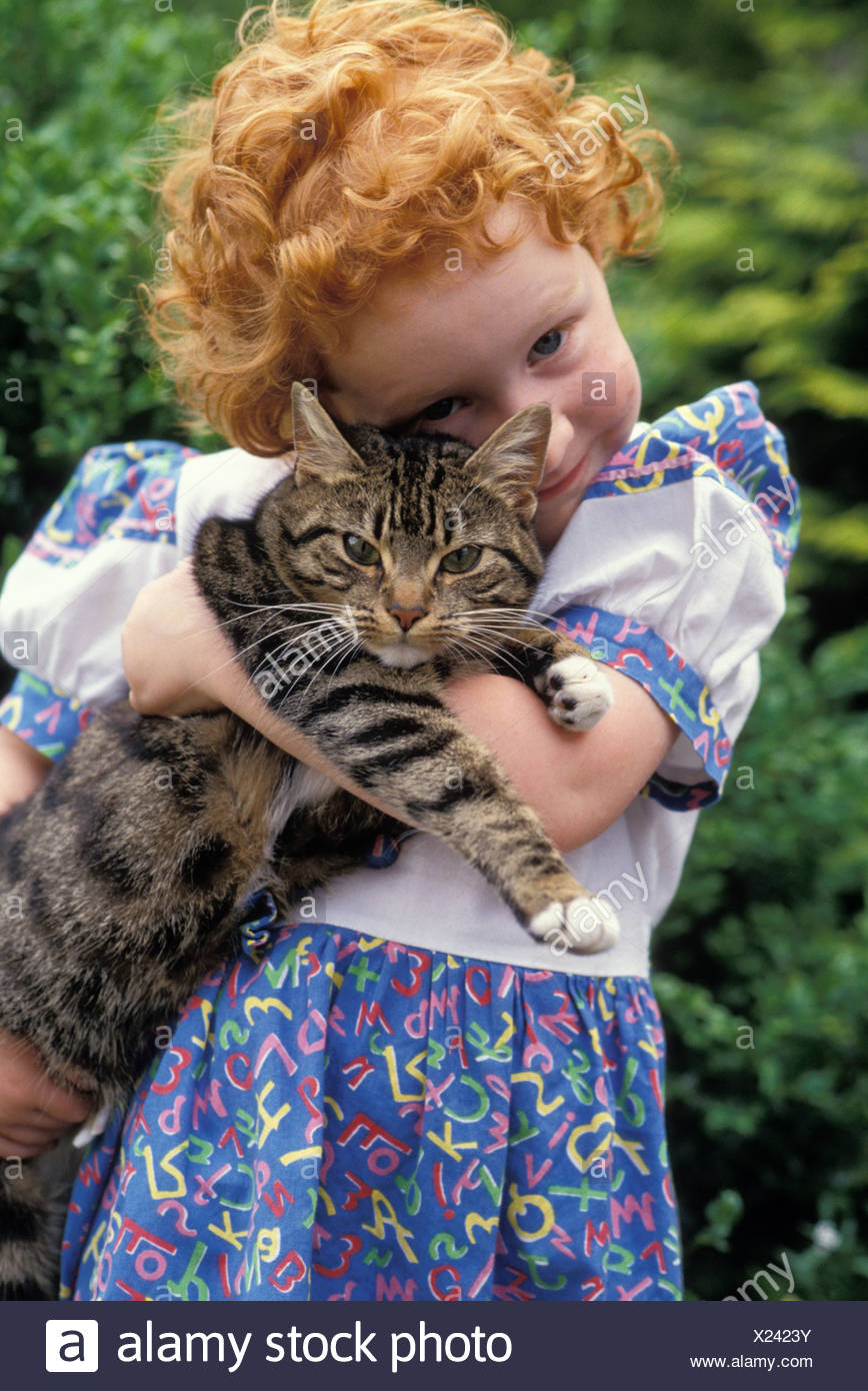 Small Girl With Red Curly Hair Wearing Purple Dress Cuddling Tabby