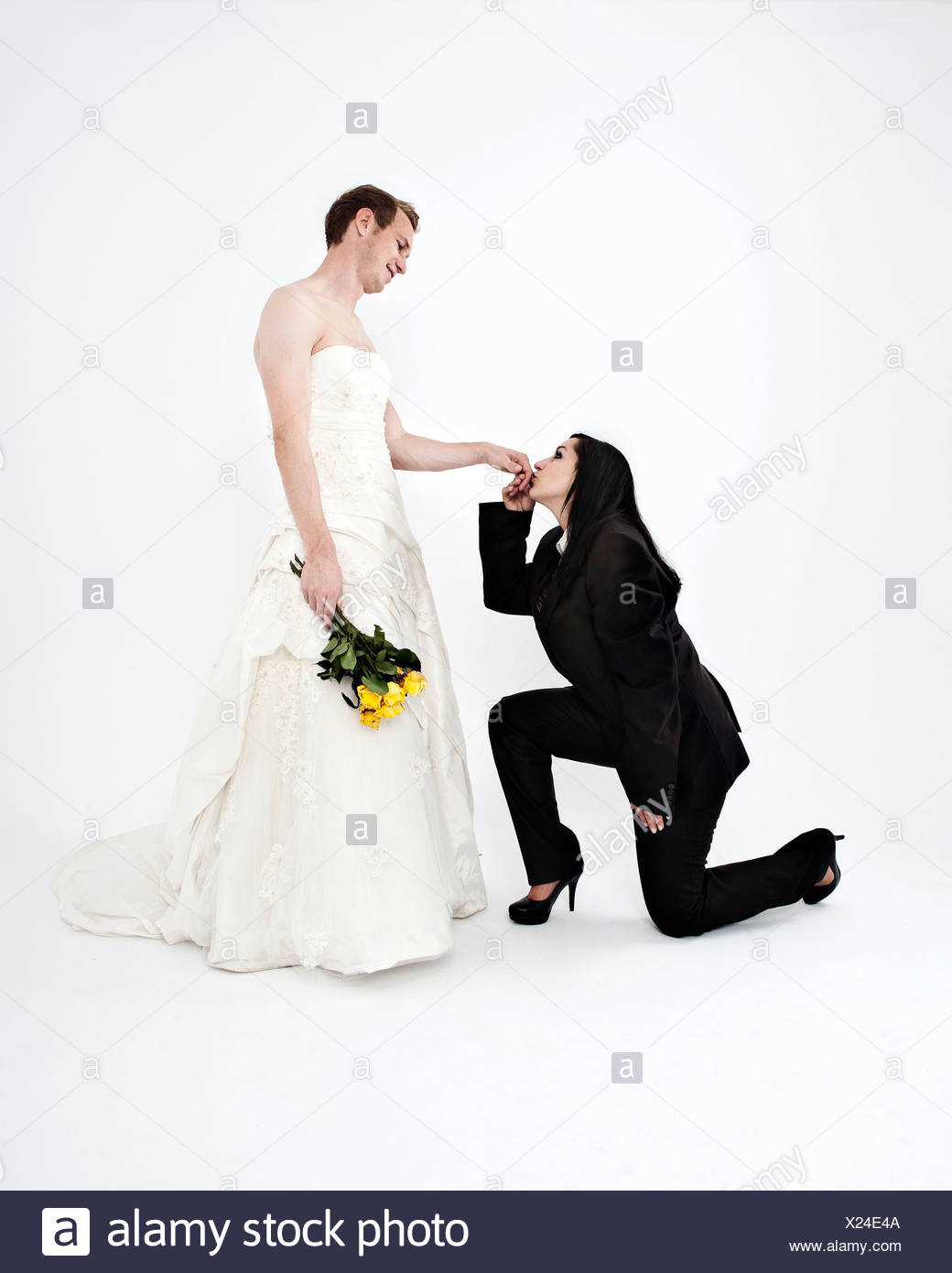 Bride Wearing A Suit Kissing The Hand Of A Groom Wearing A Wedding