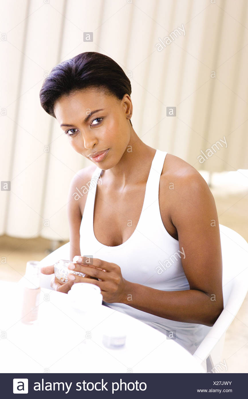 Female Short Swept Back Hair Wearing A White Vest Sitting At A