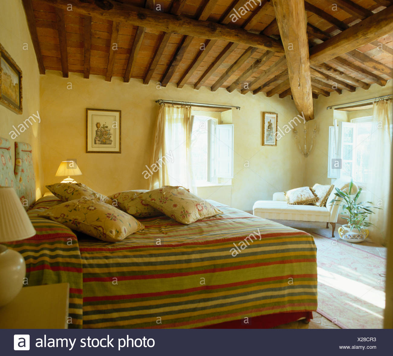 Floral Cushions And Fitted Striped Bed Cover On Bed In