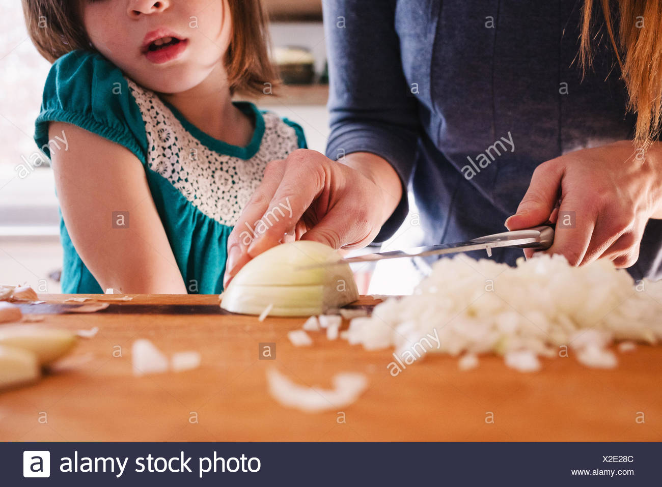 Mother teaching her daughter to chop onions Stock Photo