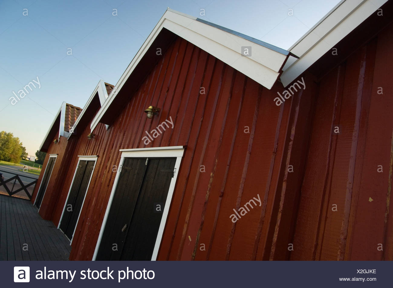 View Of Red Coastal Cottages In A Row Below Clear Blue Sky Stock