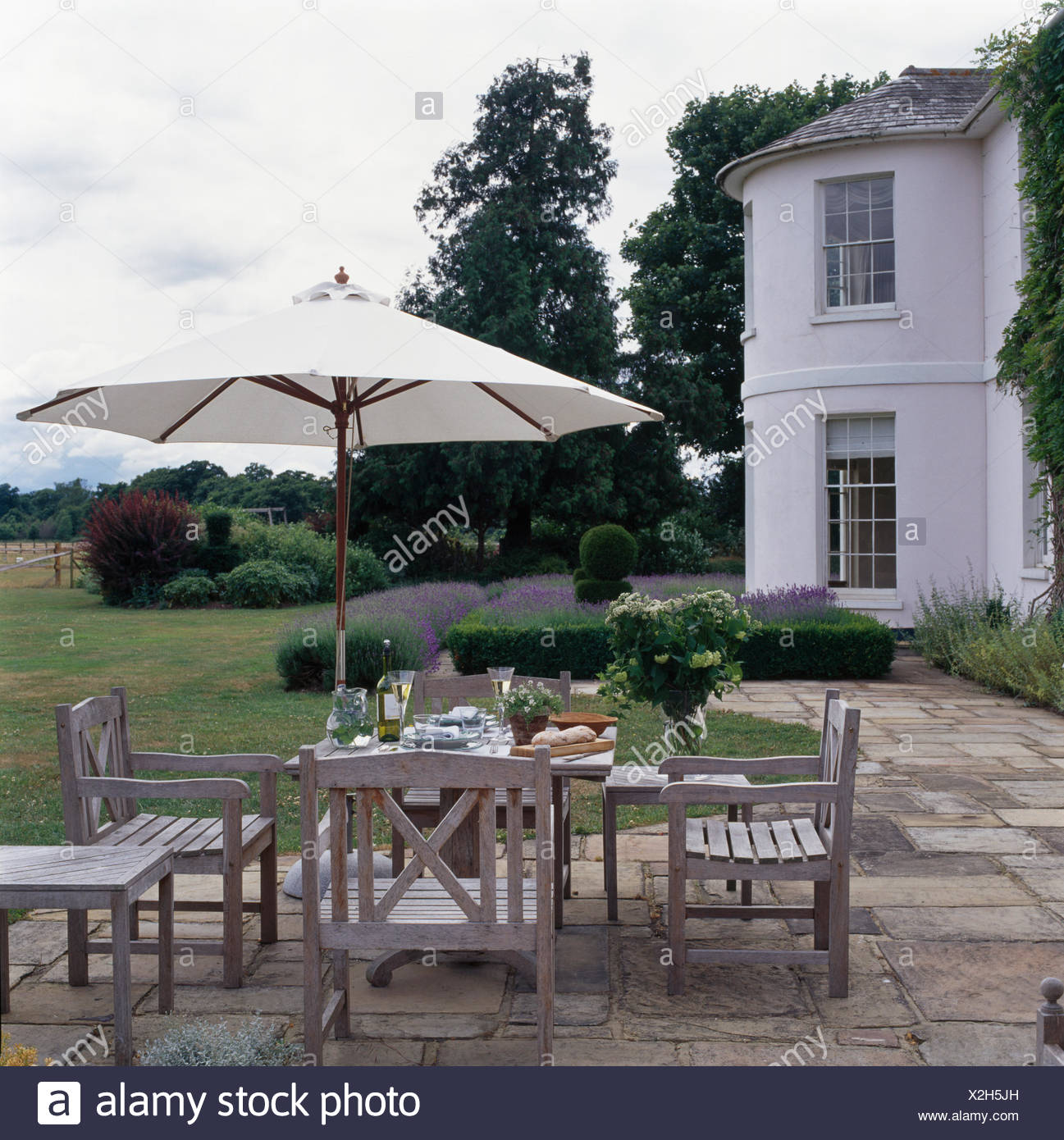 Large White Umbrella Above Wooden Table And Chairs On Paved Patio In Garden Of Large Country House Stock Photo Alamy