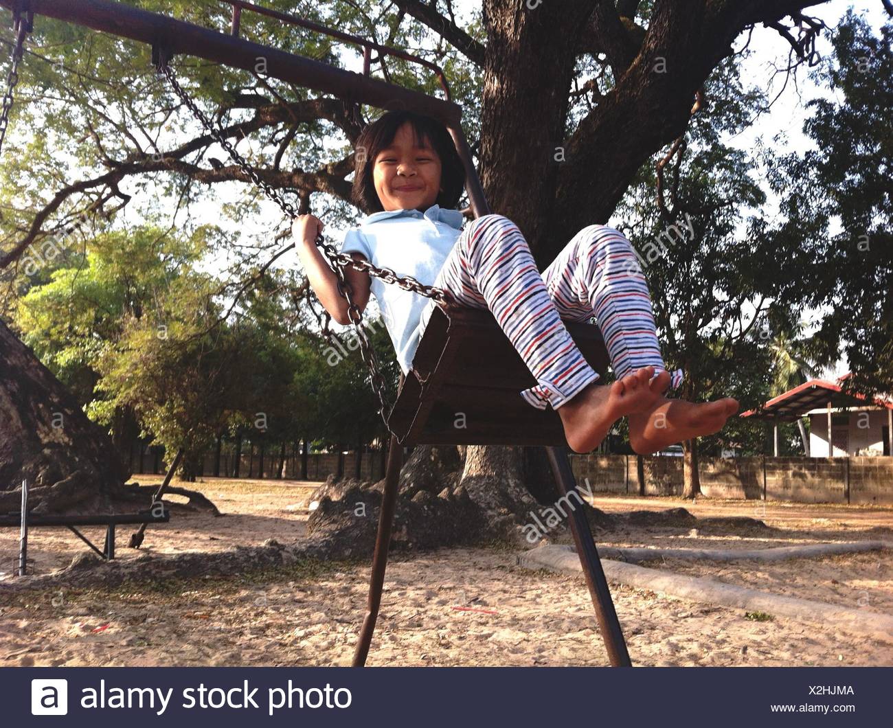 Girl Swinging On Chain Swing Ride And Smiling Stock Photo