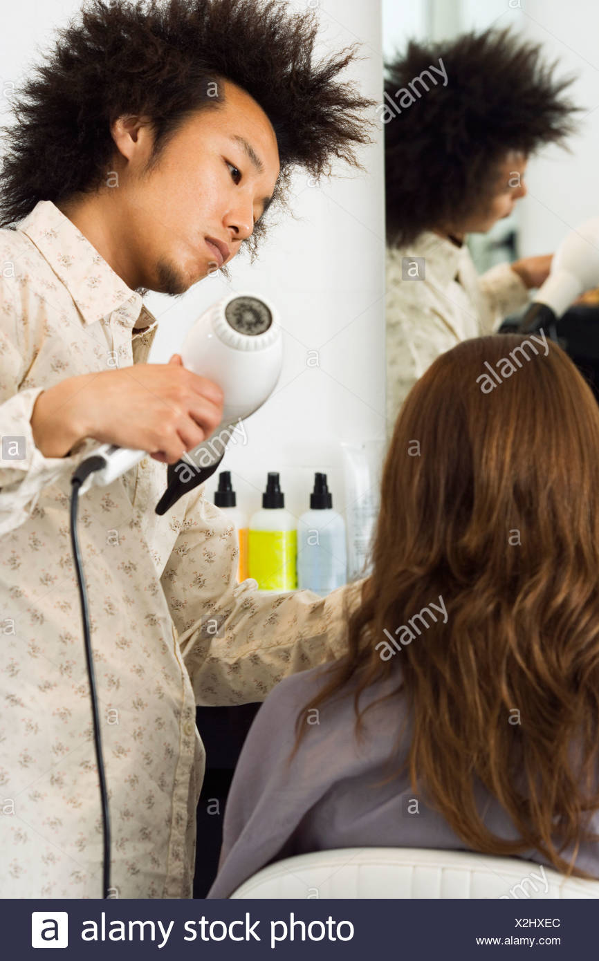 Young Male Hairdresser Blow Drying Woman S Hair With Hair Dryer In