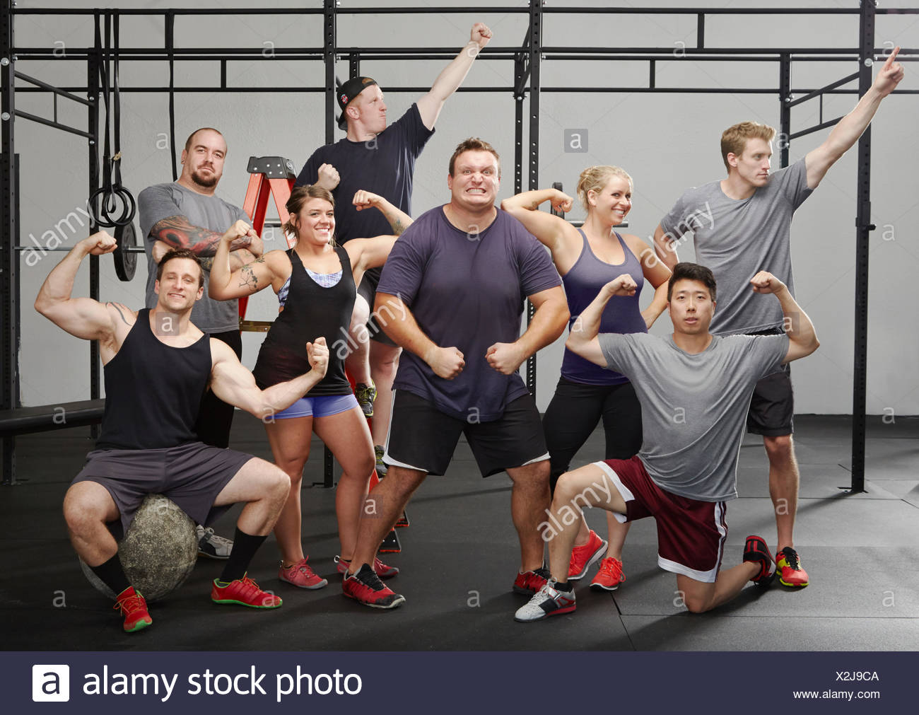 Portrait of eight people flexing muscles in gym Stock Photo